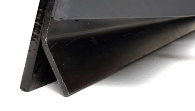 Close-up of a black metal angle iron, positioned on a white surface with one edge facing the camera, showing its L-shaped cross-section.