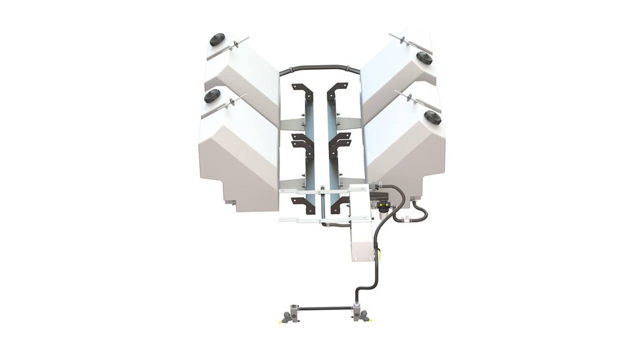 A large white industrial machine with four angular tanks, black support bars, pipes, and cables is viewed from above against a white background, showcasing its intricate engineering.