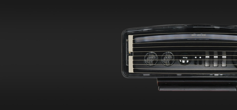 A close-up of the right half of a modern car’s rectangular LED headlight, highlighting sleek design against a plain dark background.